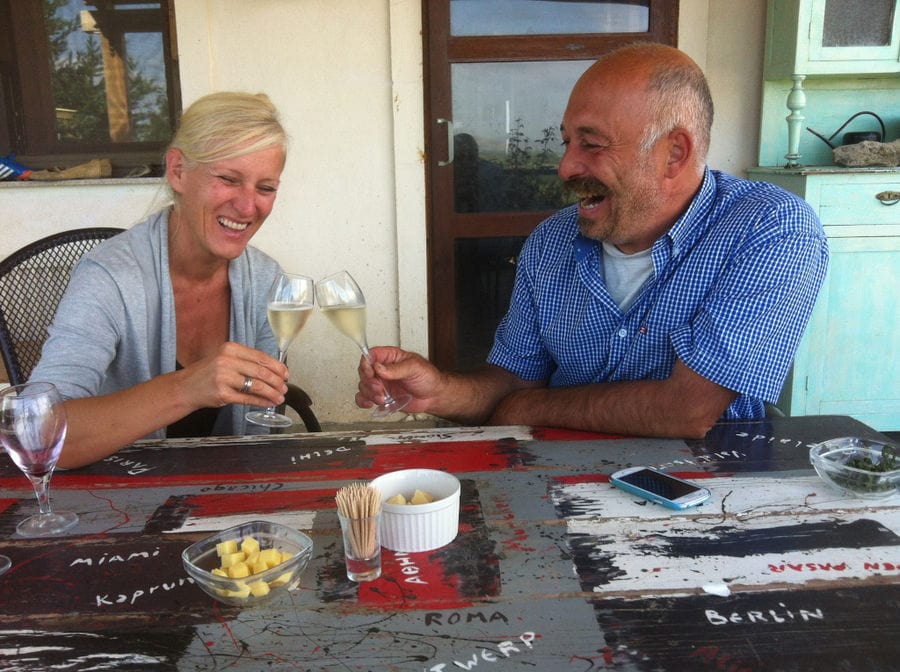 couple smiles happily wishing 'cheers' with two glasses of white wine at 'Domaine Karanika' winery
